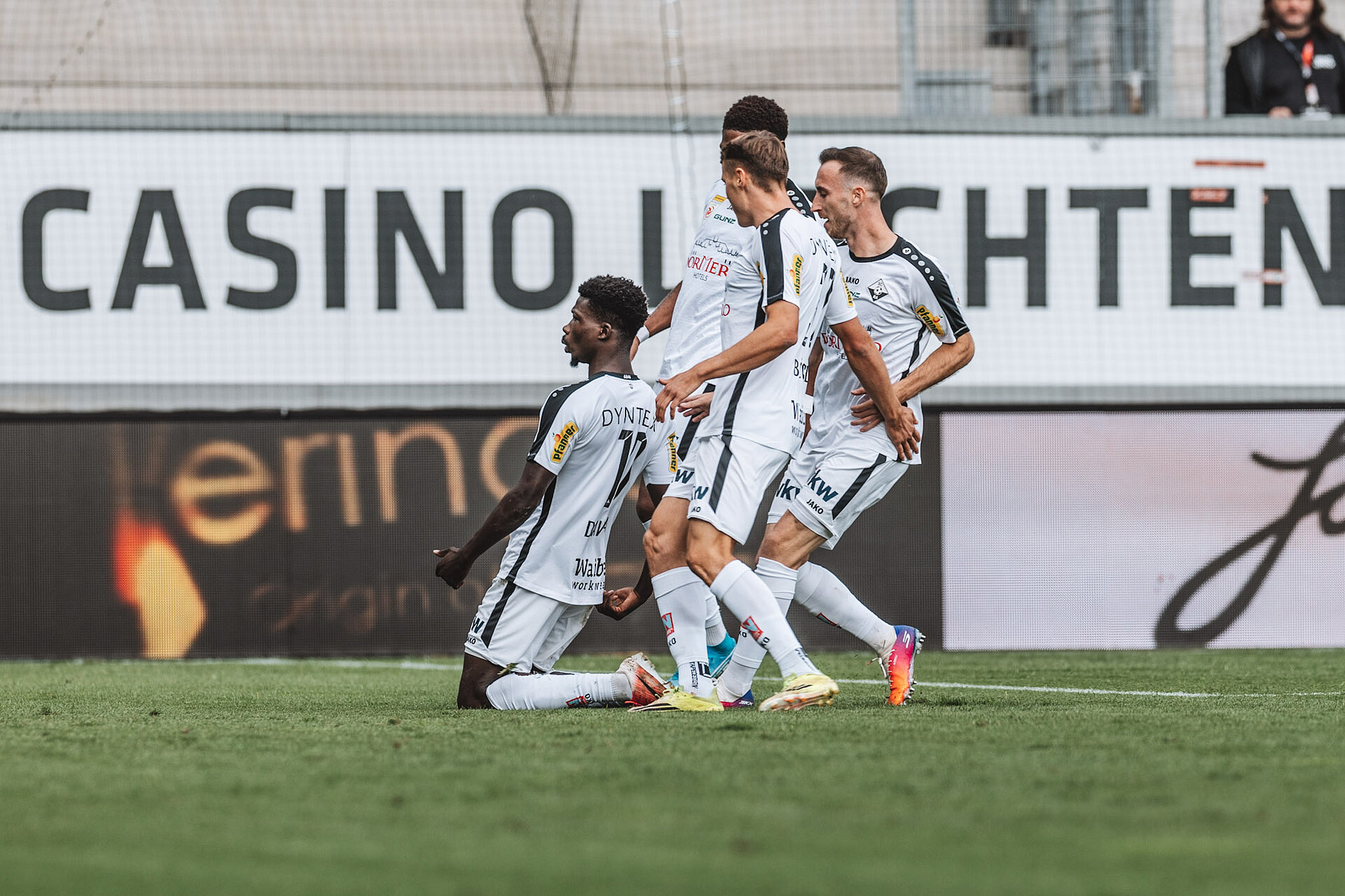 Fußballspieler von Sturm Graz feiern Torjubel vor Casino-Werbung in Graz