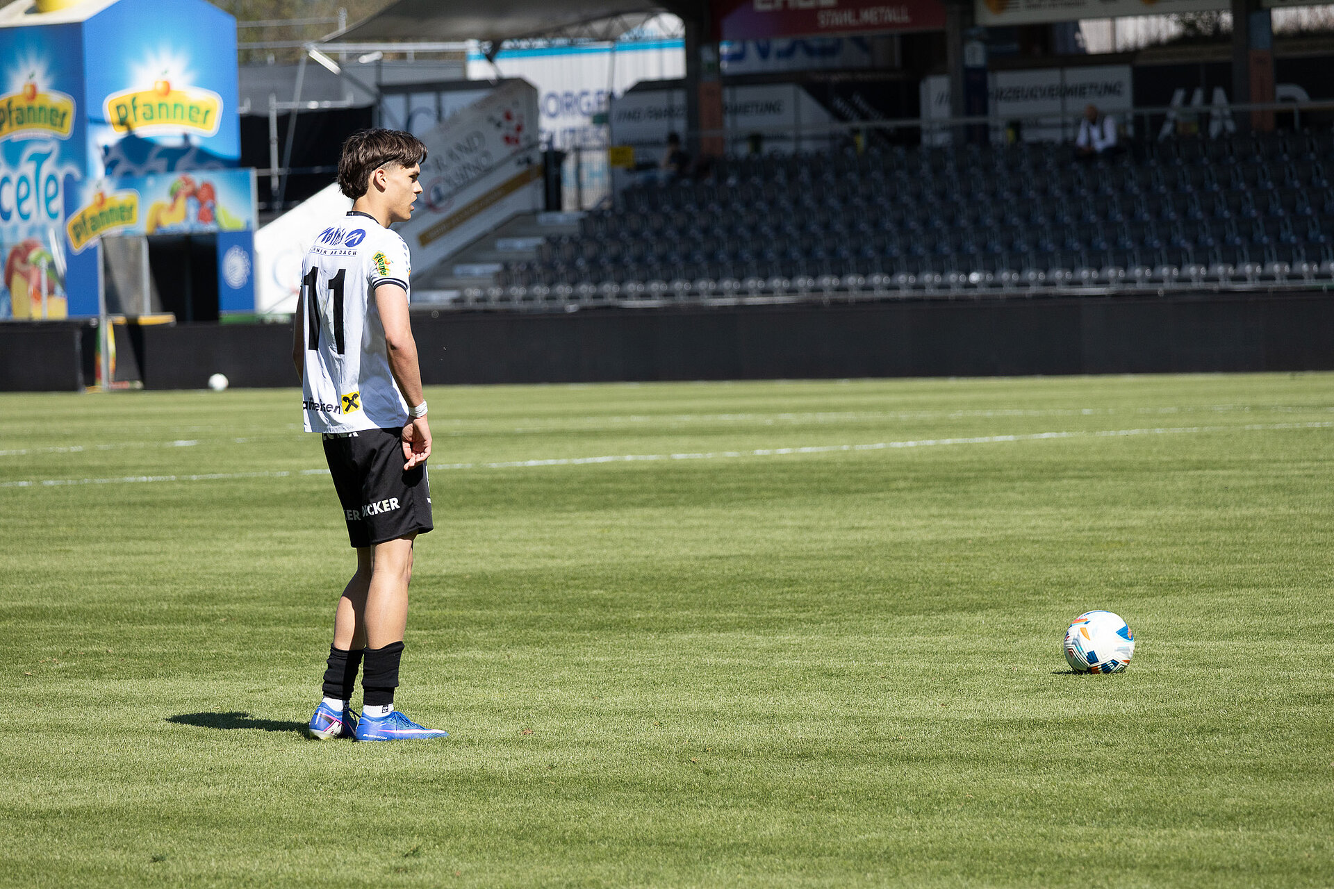 Fußballspieler mit Nummer 11 auf einem Rasen im Stadion mit Ball